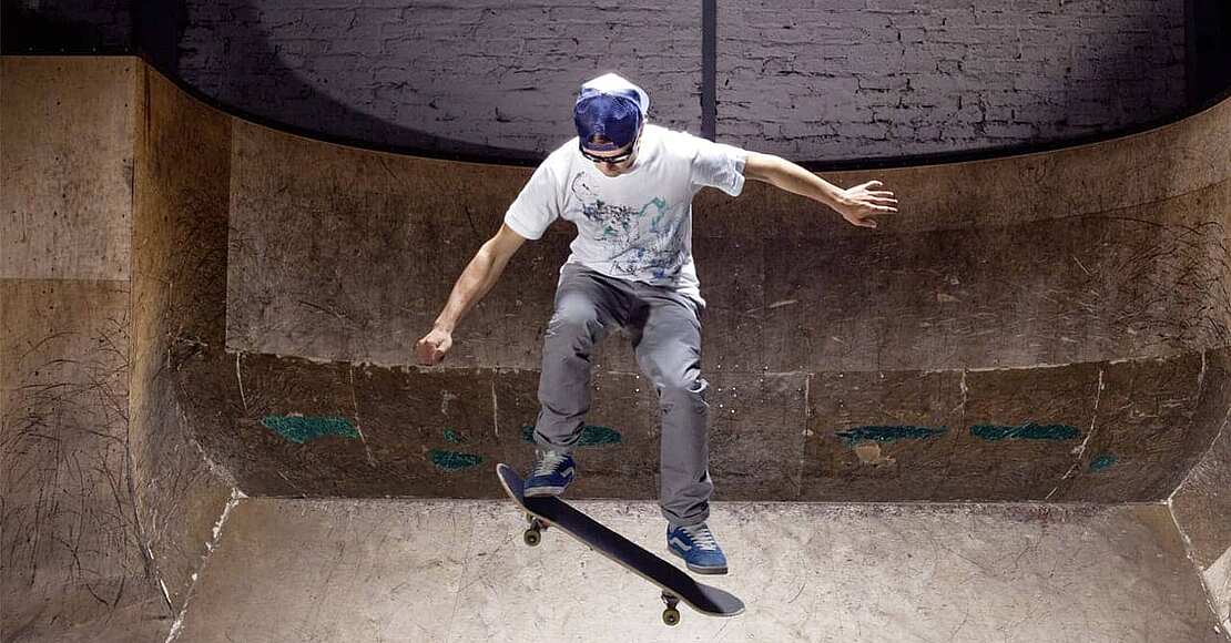 Ein Mann macht einen Trick auf dem Skateboard, während er eine Brille zum besseren Sehen während des Sportes trägt