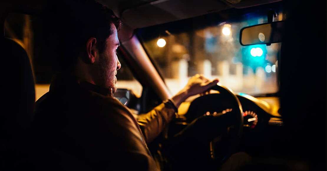Ein Mann fährt nachts mit dem Auto durch die Stadt (Nachtblindheit)