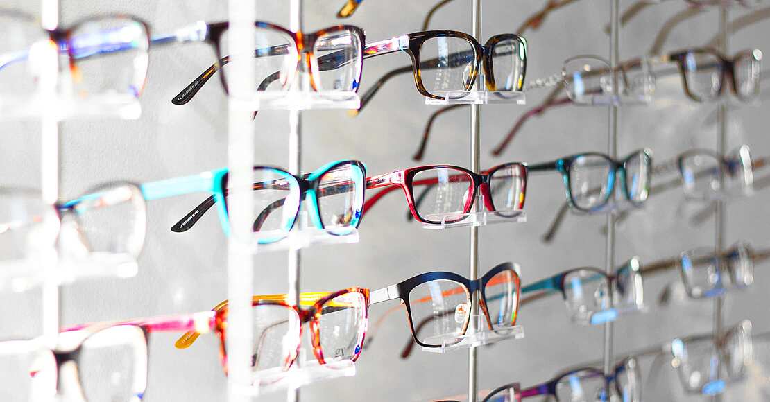 Viele Brillen mit verschiedenen Brillenfarben an einer Wand beim Augenoptiker