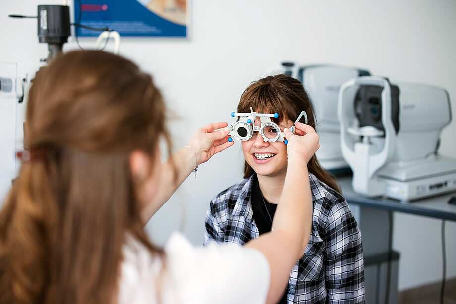 Mädchen beim Kinder-Sehtest beim Optiker mit Messbrille auf der Nase